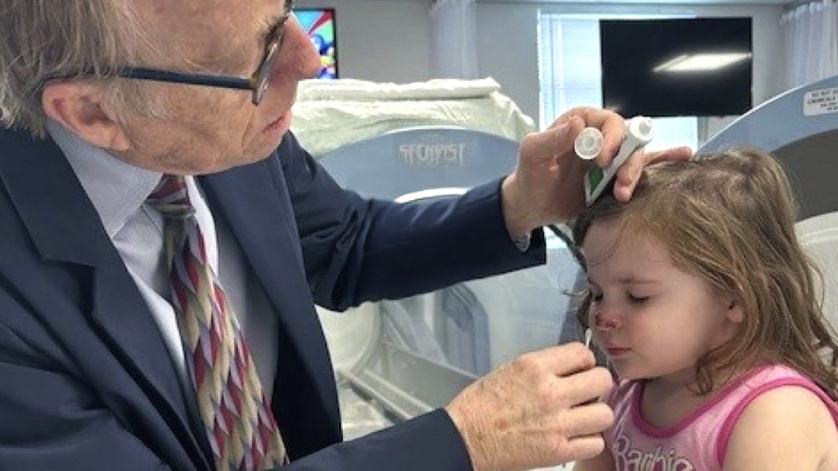 Dr. Paul Harch examines a young girl’s nose during her recovery from a severe dog bite, showcasing the healing power of Hyperbaric Oxygen Therapy (HBOT).