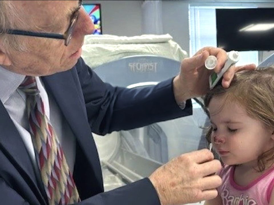 Dr. Paul Harch examines a young girl’s nose during her recovery from a severe dog bite, showcasing the healing power of Hyperbaric Oxygen Therapy (HBOT).